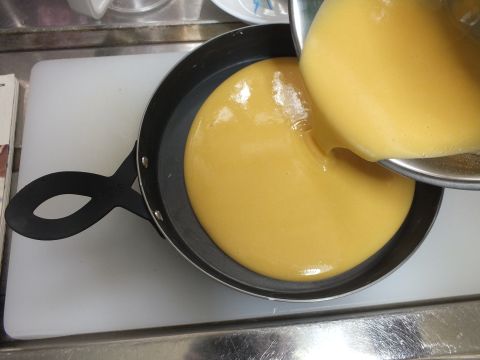 バターを塗って冷蔵庫に入れておいた型「レイエ グリルピザプレート」に生地を流し入れて、底をたたいて気泡を抜きます。