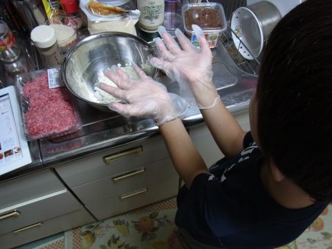 料理用手袋を着用した小2むすこにハンバーグ作りを手伝ってもらいます。